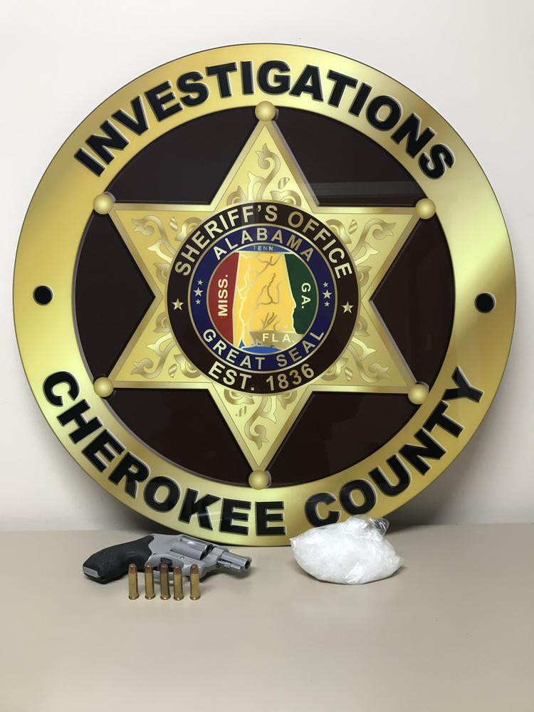 Cherokee County Investigations badge with the handgun and bag of methamphetamine seized during a traffic stop
